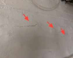 Masonry foundation surface flaking and breaking away from spalling damage