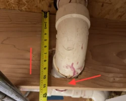 Structural floor joist with an oversized hole cut through it to pass plumbing pipe