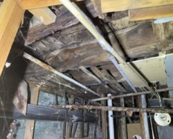 Basement floor joists with rotted and crumbling wood along their lower edges