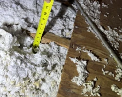 Attic floor with a shallow layer of insulation barely covering the ceiling joists