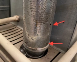 Furnace Vent – Holes in the Flue Metal furnace flue vent pipe with visible holes rusted through its wall